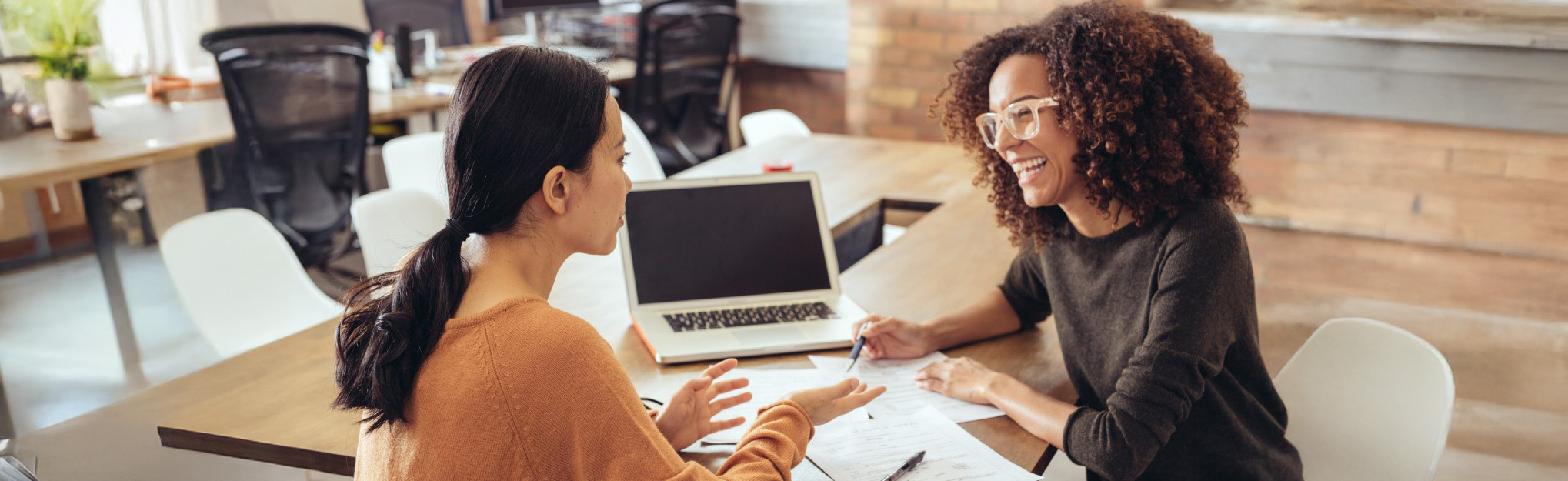 two women looking over paperwork at a desk